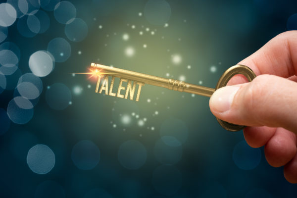 A hand holding a golden key that has a bit shaped like the word talent.