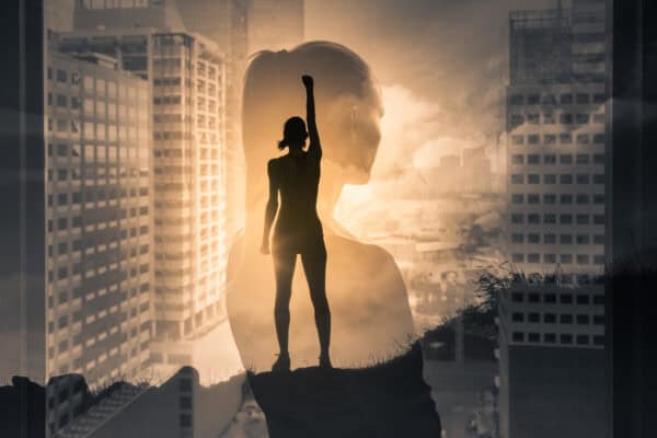 A silhouette of a woman in front of a cityscape, holding up her fist in triumph.